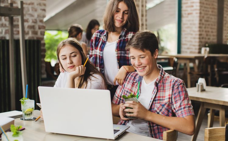 dwie nastolatki i nastolatek wpatrujący się w ekran komputera