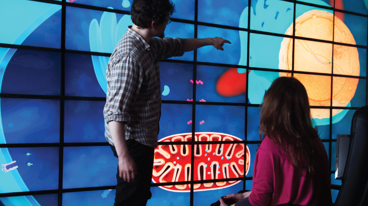 mężczyzna i dziewczynka stojący przed ekranem, na którym wyświetla się animacja